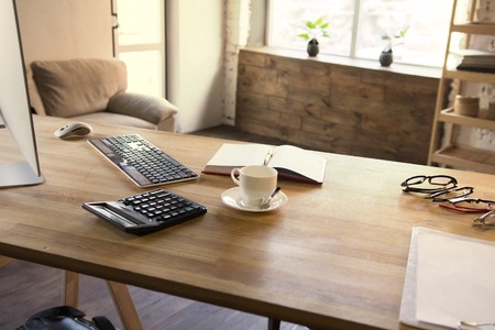 Modern office desk design. Office interior with wooden office table with several stationary items cup of coffe and pc computer on it.の写真素材