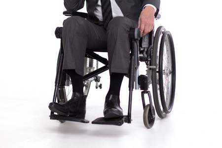 Cropped picture of disbaled man insuit. Studio shot of man sitting in wheelchair wearing fancy business outfit.の写真素材