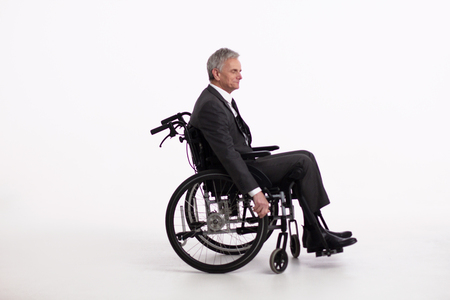 Side view of aged man sitting in wheechair. Elderly man wearing formal office clothes sitting in wheelchair and holding its wheels. Isolated on white background.の写真素材