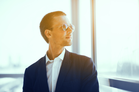 Good looking guy in sunglasses. Young stylish confident businessman wearing jacket and white collar shirt looking into distance.の写真素材