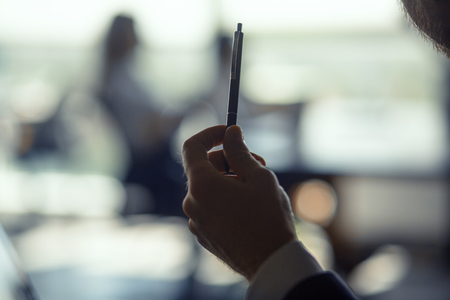 Man hand holding pencil. Working colleague on background. Business concept.の写真素材