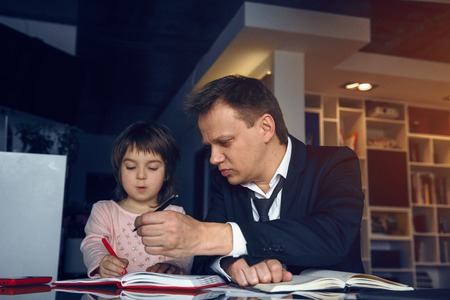 Businessman drawing together with little daughter. Having break from work. Business at home concept.の写真素材