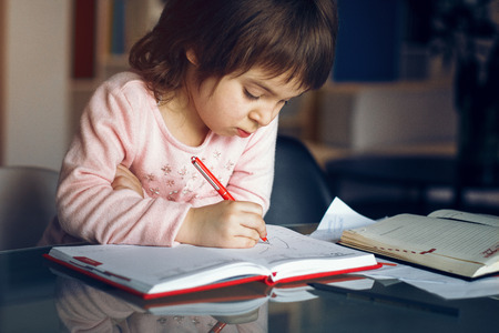Little girl drawing in her father notebook. Spending time together. Family concept.