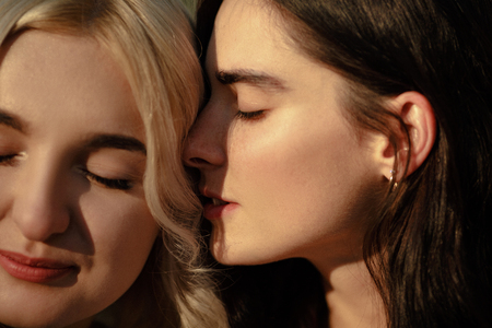 Close up of lesbian couple embracing. Girl whispering words of love to her girlfiend. Lesbian love concept.の写真素材