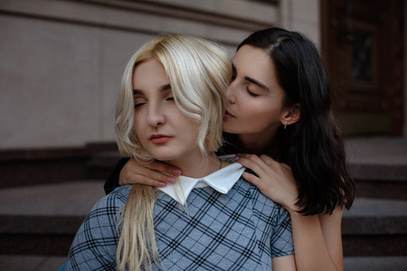Brunette lesbian embracing her girlfriend. Sitting on stairs outside. samesex love concept.の写真素材