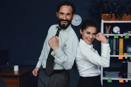 Smiling colleagues showing muscles while working in office. Business power concept.の写真素材