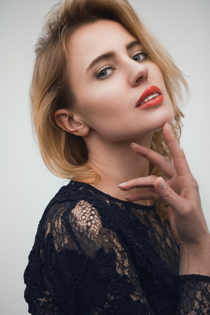 Beautiful blonde woman on white background. Pretty gorgeous woman with accurate make up looking straight into camera with soft face expression.の写真素材