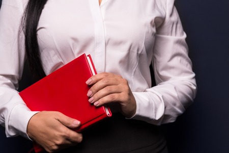 Attractive woman holding red notebook. Woman in business concept. Isolated on dark background.の写真素材