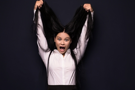 Young business woman touching her long dark hair. Relaxing after long working day.の写真素材