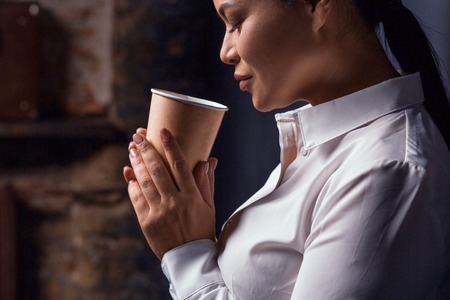 Portrait of businesswoman having coffee. Isolated on dark background.の写真素材