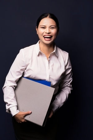 Smiling asian business woman holding folders. Wearing white blouse. Woman in business concept.の写真素材