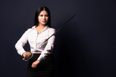 Sword in hands of business woman. Business power concept. Isolated on dark background.