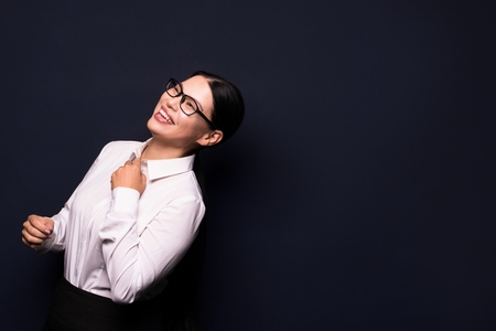 Business woman is happy at the end of working day. Smiling and looking aside. Isolated on dark background.の写真素材