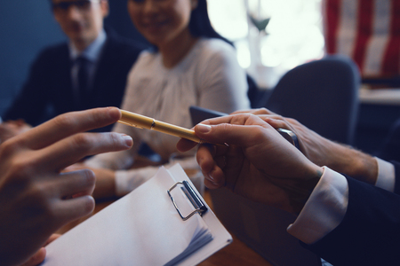 Businessman passes pen to his colleague during conference meeting. Agreement signing. Business concept.の写真素材