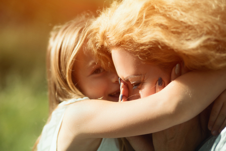 Bright Portrait. Cute Blonde Girl Hugs Tight Her Mother Who Is Crying From Happiness. Portrait Of Disabled Woman Crying When Being Hugged By Daughterの写真素材
