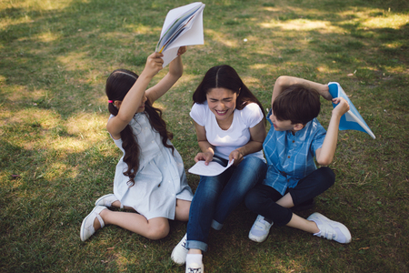 Children Are Fighting With Copy Books While Having Lesson In Park. Creative Lesson Concept.の写真素材
