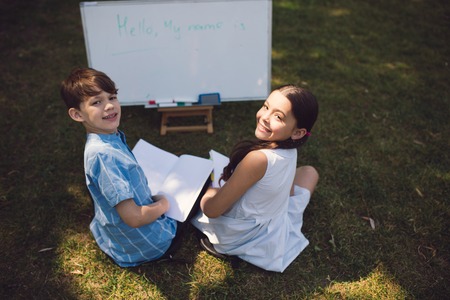 School Children Sitting On Grass And Having Maths Lesson. Writing On Whiteboard. Education In Nature Concept.の写真素材