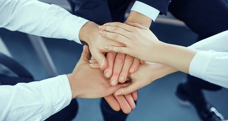 Male and female office workers, colleagues, teams folded in one pile. Top view on the hands united togetherの写真素材