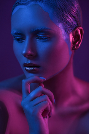 Sad Girl with Creative Make Up in Blue and Purple Lights of Neon on Dark Backgroundの写真素材