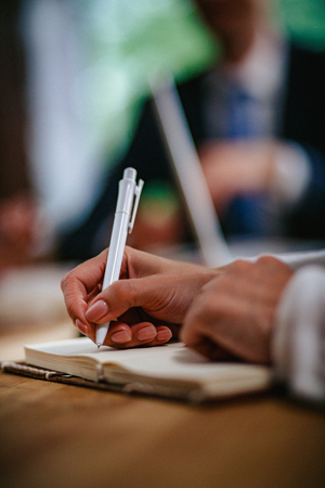 Business woman in the office at the table. She writes a new business plan in her notebook. Close-up shotの写真素材