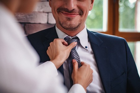 Business woman flirts with a work colleague. They talk and she straightens his tie. Close-up shotの写真素材
