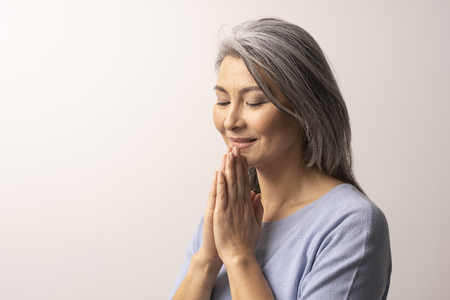 Mongolian Woman of Nationality is Thinking About Something. Woman Looks Cute Smiling. Her Hands are Gently Folded in the Palm. Mongolian Beauty Concept. Close Up Shoot.の写真素材