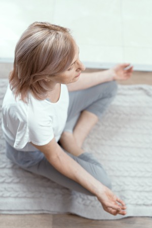 After Yoga a Woman Meditates. Age of the Woman for 50 Years. She Has Been Doing Yoga at Home for a Long Time. Close Up Shot.の写真素材