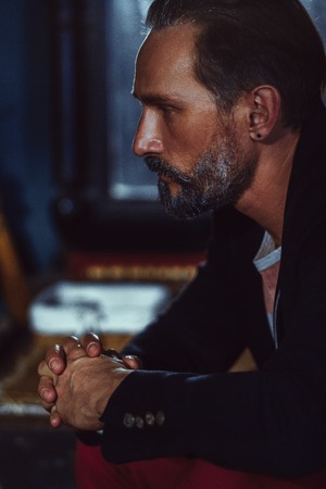 Close Up Profile of a Handsome Man With a Beard. The Man Has a Thoughtful Look. He is Wearing a...