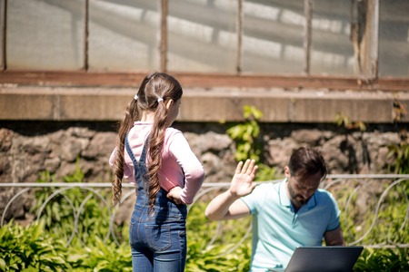 Young Daughter Asking For Laptop In Father While He Working On It. Father Refusing By Raising Hand.の写真素材