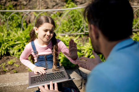 Girl Giving Five To father After Getting Laptop From Him. Going To Play Computer Games In Summer Park.の写真素材