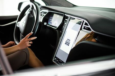 Tesla Salon Inside View. Future Technologies of New Generation Electric Vehicle. Girl Sitting Behind...