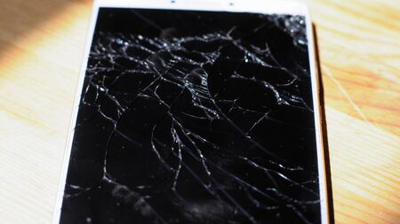 Xiaomi MI Max smartphone with broken screen matrix lies on wooden table. Closeup photoshot shows chaotic shining fractures on black display Kyiv, Ukraine, 6th of June 2019のeditorial素材