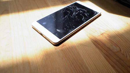 Xiaomi MI Max smartphone with broken screen matrix lies on wooden table. Sunlight emphasizes concequences of falling accident Kyiv, Ukraine, 5th of June 2019のeditorial素材