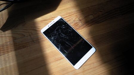 Xiaomi MI Max smartphone with broken screen matrix lies on wooden table. Sunlight emphasizes concequences of falling accident Kyiv, Ukraine, 5th of June 2019のeditorial素材