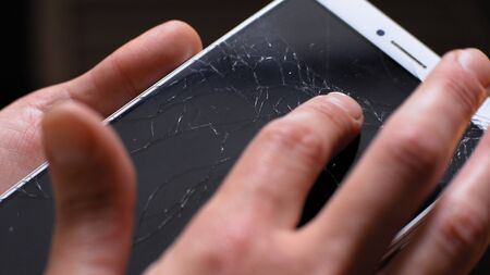 Man holding Xiaomi MI Max smartphone with broken screen in his hands. He is turning phone on sunlight to see fractures better and points on them with his finger Kyiv, Ukraine, 5th of June 2019のeditorial素材