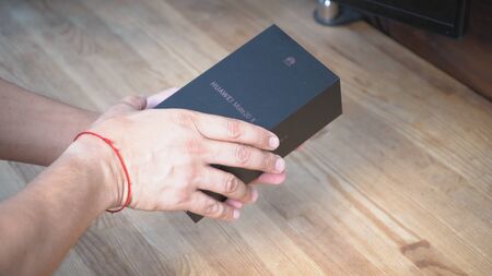 Man is getting ready to open box. His hands are holding cap of phones package Kyiv, Ukraine 15th of June 2019のeditorial素材