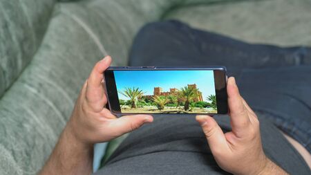 Man lying on couch and watching video about nature and arabian architecture in high definition...