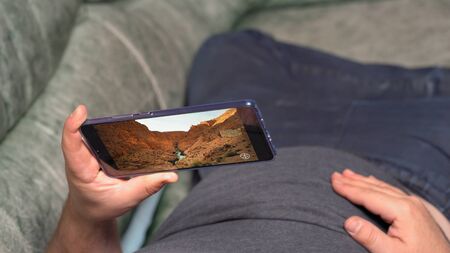 Man lying on couch and watching video about canyon valley in high definition through Huawei Mate 20...