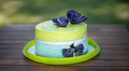 Double layered mint besquit decorated with blue edible flowers on the wooden table at the garden