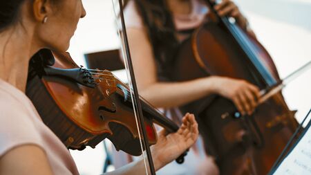 String Group Of Female Musicians Playing On The Summer Terrace Outside, Violin And Bow Close UP