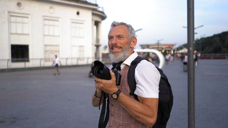 A Middle-Aged Man With A Backpack Admires The Beautiful View Of The City Preparing To Take A Picture.の写真素材