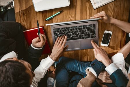 Business Team Working Together On Strategy Of New Start Up Project, Unrecognizable Male And Female Person Looks At Laptop Sitting At Wooden Table In Office, High Angle View, Toned Imageの写真素材