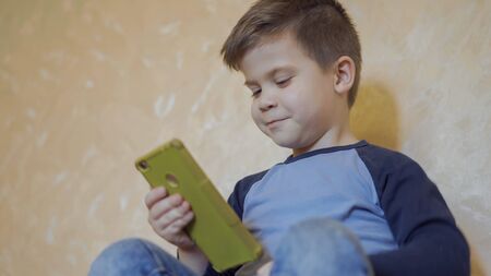 Pre-school children use a mobile phone to video chat with friends online. Quarantine concept....