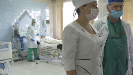 Group of doctors in resuscitation ward. Team of doctors examines patients and prescribes medical treatment. City Hospital. May, 2020, Brovary, Ukraine.のeditorial素材