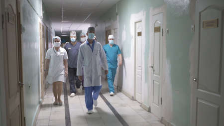 Group of doctors walking along hospital corridor. A team of medical workers in uniforms walking along hall. City Hospital. May, 2020, Brovary, Ukraine.のeditorial素材