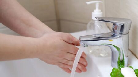 Woman washes her hands. Close up shot. Woman is about to wash her soapy hands under stream of warm...