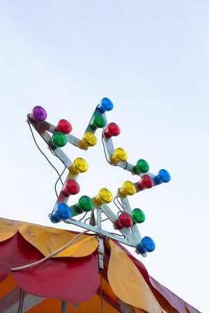 Lamp with multi-colored light bulbs. Star-shaped illumination at the top of the carousel. Illumination concept.の写真素材