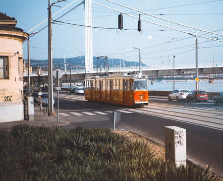 Embankment in Budapest. Lonely red tram and some cars on a deserted street on a warm sunny day, against the background of the Danube River. May, 2013. Budapest, Hungary.のeditorial素材