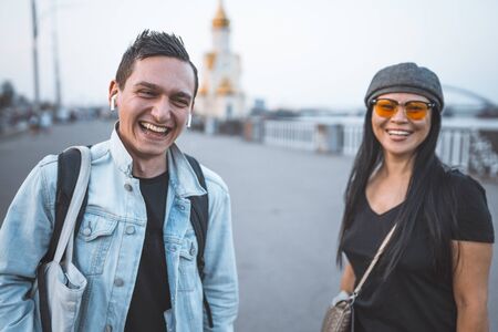 Couple of tourists with suitcase on embankment of river. Happy man and woman laughs looking at the...