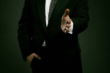 Businessman ready for handshake. Man giving his hand forward, other hand in his pocket. Highlighted...